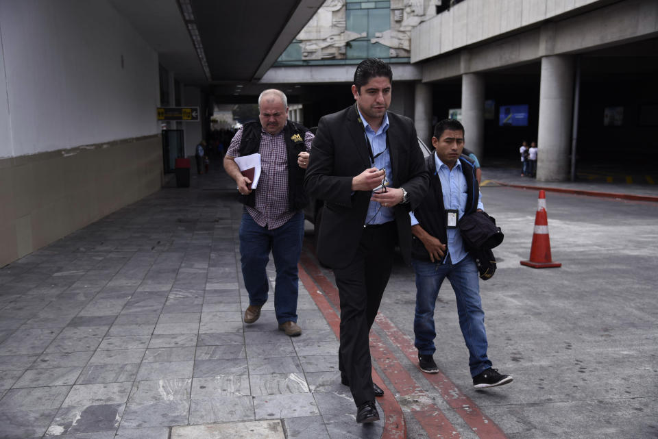 Prosecutor Stuardo Campo, with the Attorney General's office, center, leaves La Aurora International Airport in Guatemala City, Sunday, Jan. 6, 2019. Authorities are holding Colombian national Yilen Osorio, a member of CICIG, in the capital's airport, refusing him entry to the country in an escalation of tensions between the government and the commission. (AP Photo/Santiago Billy)