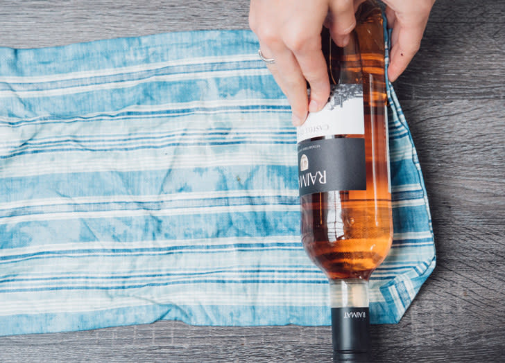 Rolling a wine bottle in a wet dish towel.