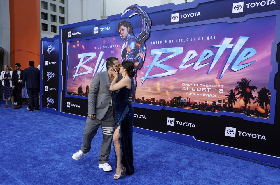 Ángel Manuel Soto, director de "Blue Beetle" se besa con su esposa Carla González, en una función de la película el 15 de agosto de 2023, en el Teatro Chino TCL en Los Angeles. (Foto AP/Chris Pizzello)