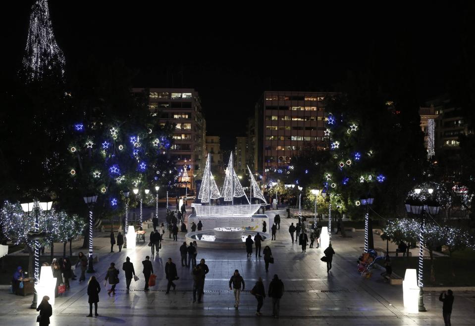 People walk past an illuminated boat, which is part of this year's Christmas decorations, at Syntagma square in central Athens