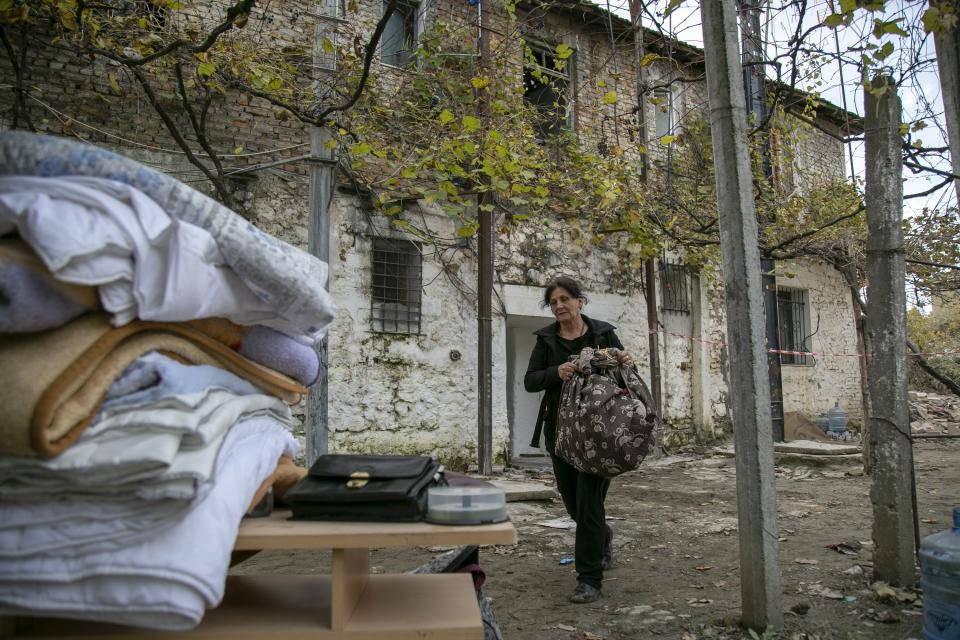 A woman carries her belongings from a damaged house in Thumane, western Albania, Friday, Nov. 29, 2019. The operation to find survivors and recover bodies from Albania's deadly earthquake was winding down Friday as the death toll climbed to 49. (AP Photo/Visar Kryeziu)