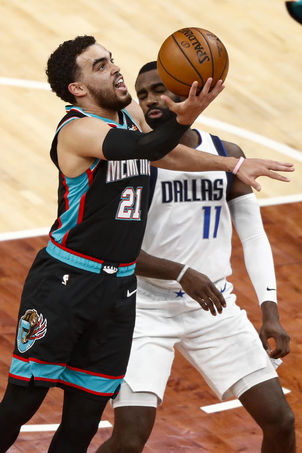 Memphis Grizzlies guard Tyus Jones (21) shoots past Dallas Mavericks forward Tim Hardaway Jr. (11) during the first half of an NBA basketball game Tuesday, May 11, 2021, in Memphis, Tenn. (AP Photo/Wade Payne)