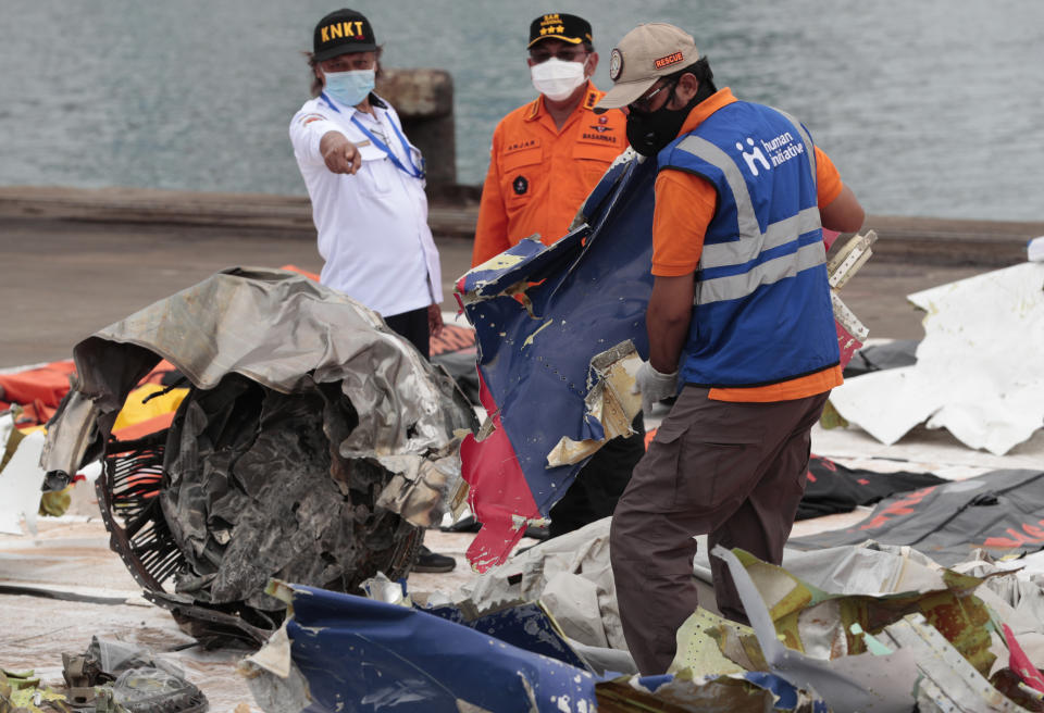 A worker carries parts of aircraft and debris retrieved from from the Java Sea where a Sriwijaya Air jet crashed on Saturday, at Tanjung Priok Port in Jakarta, Indonesia, Thursday, Jan. 14, 2021. An aerial search for victims and wreckage of a crashed Indonesian plane expanded Thursday as divers continued combing the debris-littered seabed looking for the cockpit voice recorder from the lost Sriwijaya Air jet. (AP Photo/Dita Alangkara)