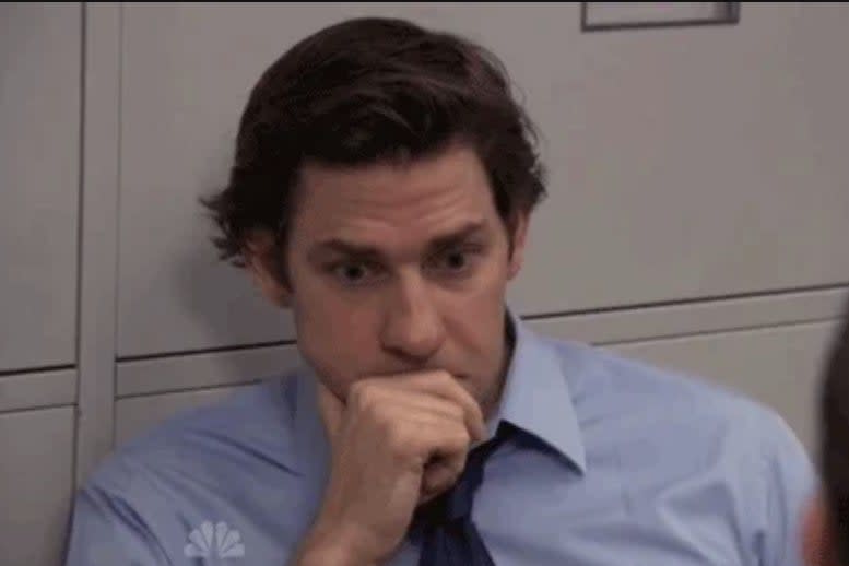 Man in an office setting looking thoughtful, resting his head on a clenched hand, seemingly pondering or concerned