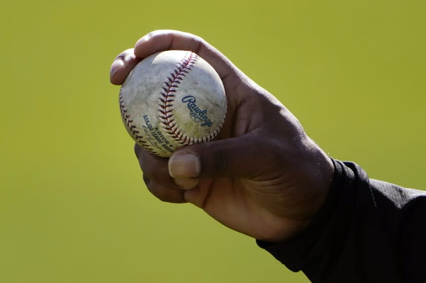 FILE - A Colorado Rockies pitcher shows his grip to a teammate during a spring training baseball workout in Scottsdale, Ariz., in this Wednesday, Feb. 24, 2021, file photo. Pitchers will be ejected and suspended for 10 games for using illegal foreign substances to doctor baseballs in a crackdown by Major League Baseball that will start June 21. The commissioner's office, responding to record strikeouts and a league batting average at a more than half-century low, said Tuesday, June 15, 2021, that major and minor league umpires will start regular checks of all pitchers, even if opposing managers don't request inspections. (AP Photo/Jae C. Hong, File)