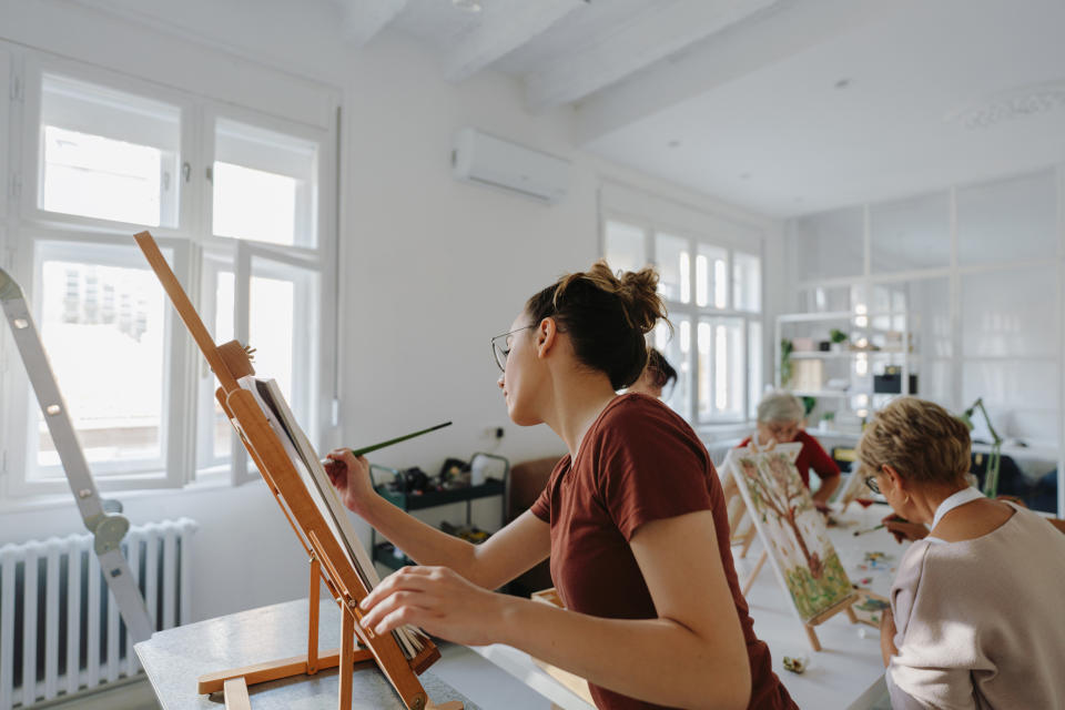 People painting on canvases in a bright studio