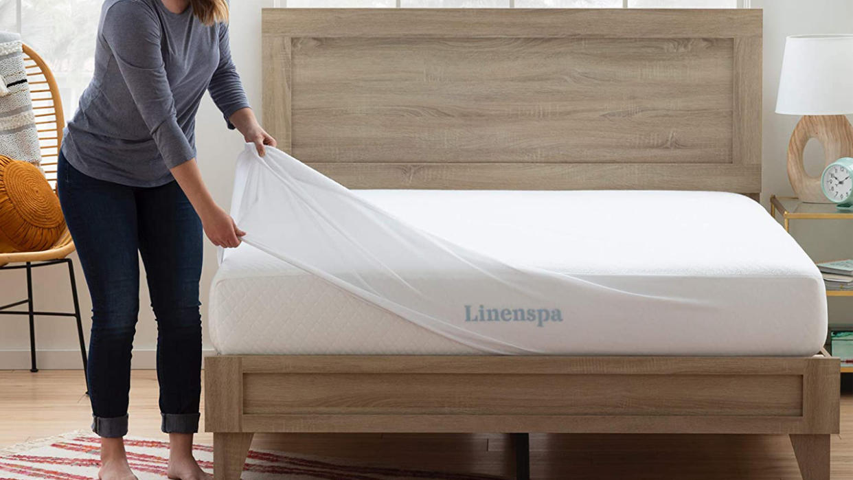  Best mattress protector 2022: a woman fits a white mattress cover over her Linenspa memory foam mattress 