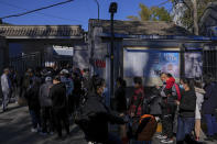 Residents wearing face masks to help curb the spread of the coronavirus line up to receive booster shots against COVID-19 at a vaccination site with a billboard displaying a propaganda poster supporting the Beijing 2022 Winter Olympic Games, near a residential area in Beijing, Friday, Oct. 22, 2021. China's capital Beijing has begun offering booster shots against COVID-19, four months before the city and surrounding regions are to host the Winter Olympics. (AP Photo/Andy Wong)