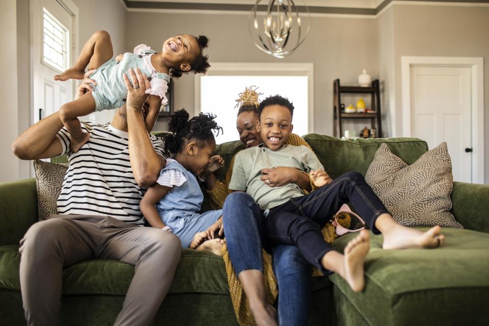 Family of five playing on sofa at home