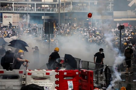 Protesters react to a tear gas during a demonstration against a proposed extradition bill in Hong Kong