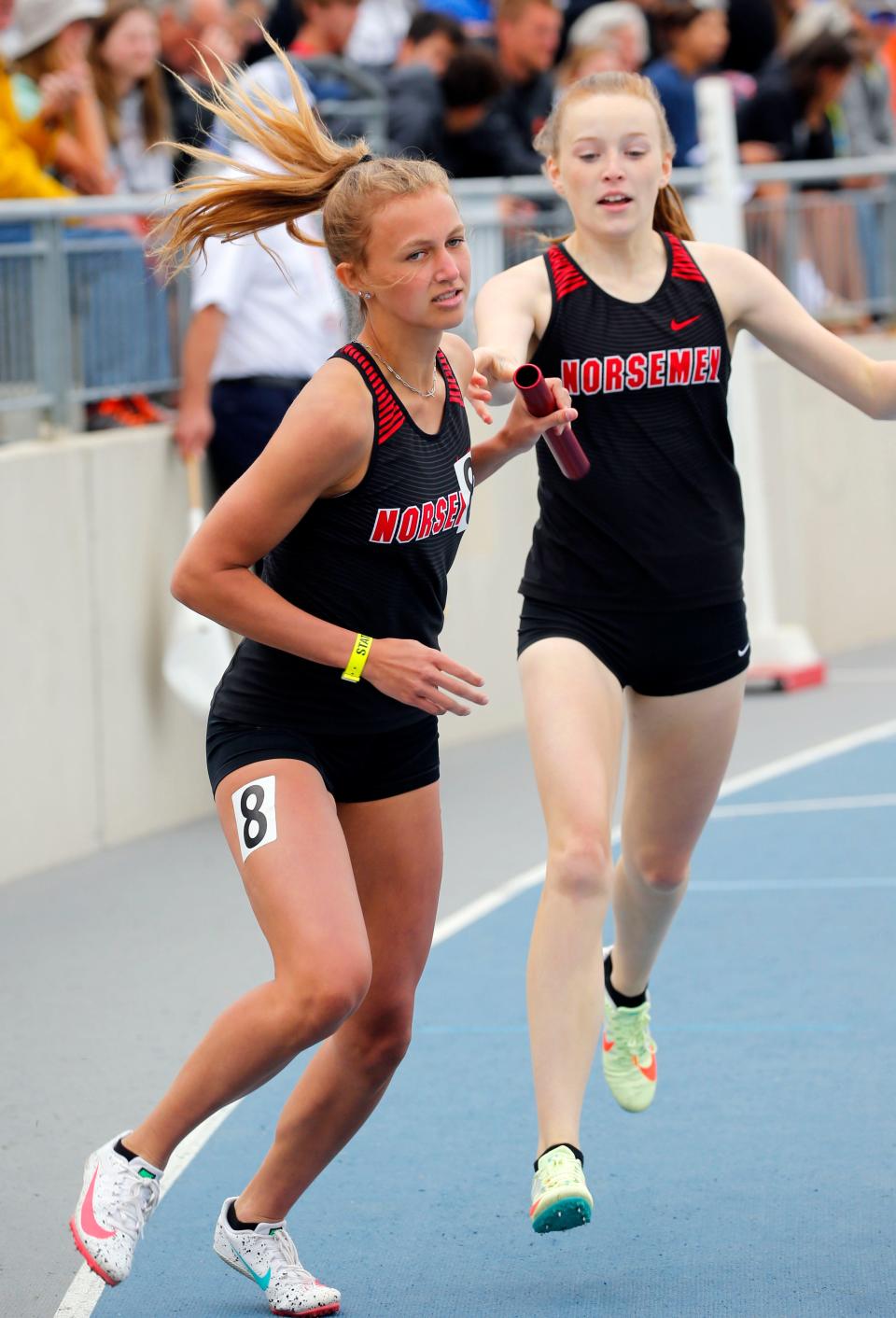Roland-Story's Kennedy Petersen (rear) and Kamryn Lande make an exchange during the 2A girls distance medley relay at the state co-ed track meet in Des Moines Friday.