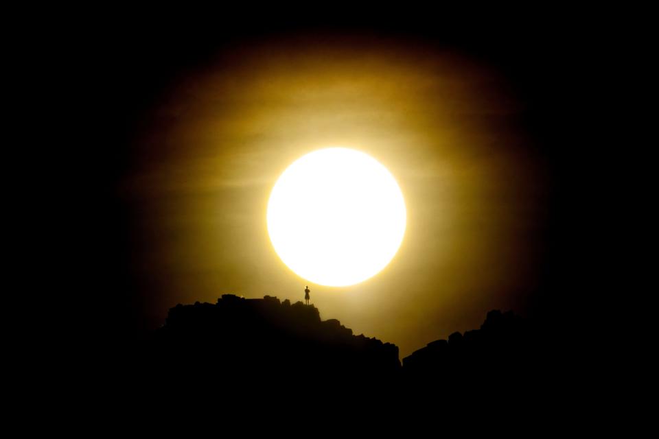 Climbers watch the sunrise on the summit of Piestewa Peak on July 15, 2023.