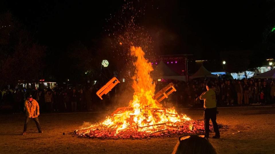 Firefighters throws a pallet onto the giant bonfire at Paso Robles’ New Year’s Eve celebration in the Downtown City Park on Dec. 31, 2023.