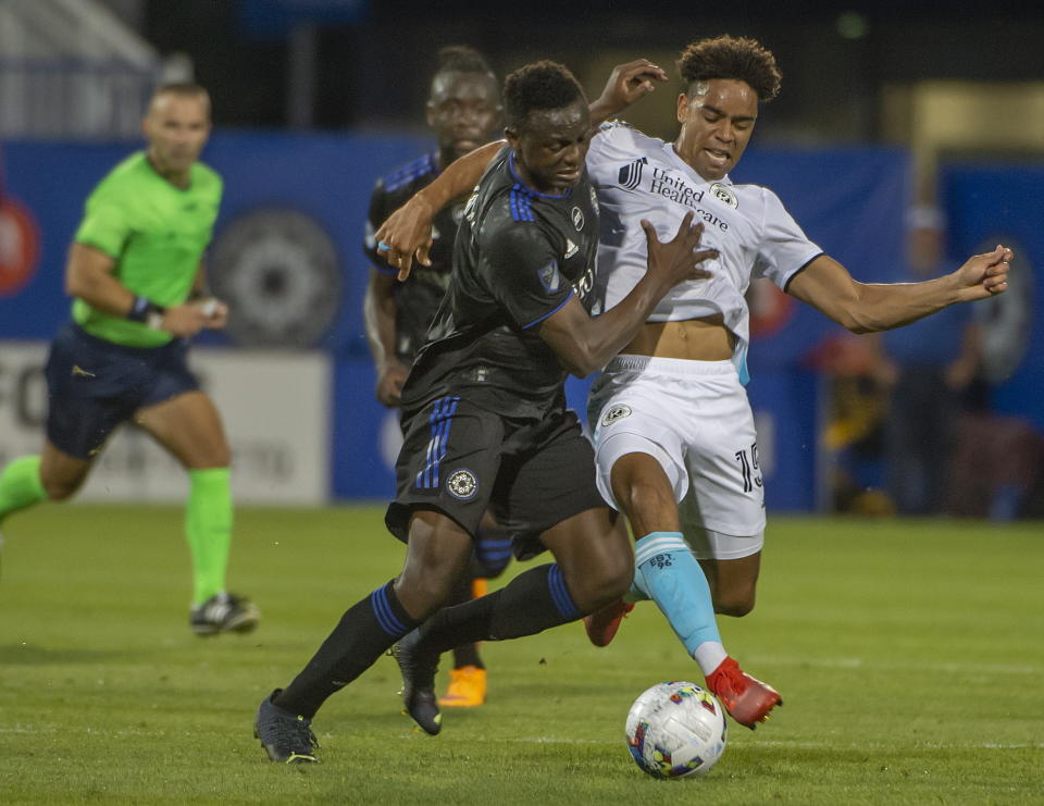 CF Montreal's Victor Wanyama, left, battles New England Revolution's Brandon Bye during first-half MLS soccer match action in Montreal, Saturday, Aug. 20, 2022. (Peter McCabe/The Canadian Press via AP)