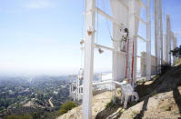 FILE — Jesus Pelayo, top, and other workers from Duggan Construction apply new paint to the "Y" in the Hollywood sign on Sept. 29, 2022, in Los Angeles. The Hollywood sign is getting a makeover befitting its status as a Tinseltown icon. After a pressure-wash and some rust removal, workers this week began using 250 gallons of primer and white paint to spruce up the sign ahead of its centennial next year. (AP Photo/Chris Pizzello, File)