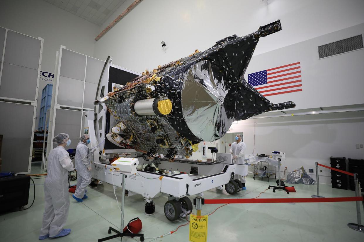  Technicians work on NASA's Psyche spacecraft inside a clean room. 