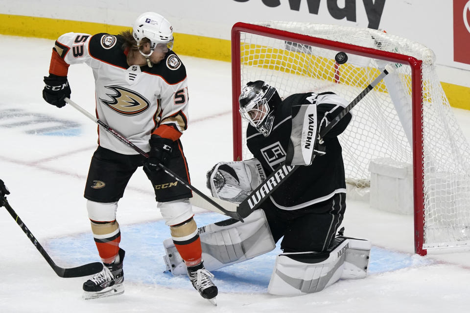 Los Angeles Kings goaltender Calvin Petersen, right, stops a shot behind Anaheim Ducks left wing Max Comtois (53) during the first period of an NHL hockey game Tuesday, April 20, 2021, in Los Angeles. (AP Photo/Marcio Jose Sanchez)