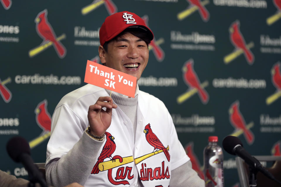 Pitcher Kwang-Hyun Kim smiles as he holds up a sign thanking his old baseball team, SK Wyverns, during a news conference announcing his signing to the St. Louis Cardinals Tuesday, Dec. 17, 2019, in St. Louis. The Cardinals have signed the Korean left-hander to a two-year contract. (AP Photo/Jeff Roberson)