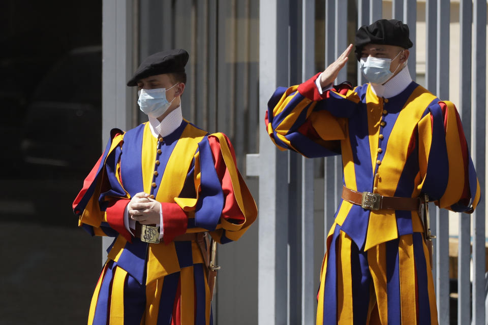 Swiss Guard stand at the entrance of the Vatican Monday, May 4, 2020. The Vatican is postponing the annual swearing-in ceremony for its new crop of Swiss Guards, a commemoration usually held each May 6 to honor the guardsmen who died while protecting the pope during the 1527 Sack of Rome. The Swiss Guards said Monday that due to the ongoing coronavirus emergency, the pomp-filled ceremony will now be held Oct. 4. (AP Photo/Alessandra Tarantino)