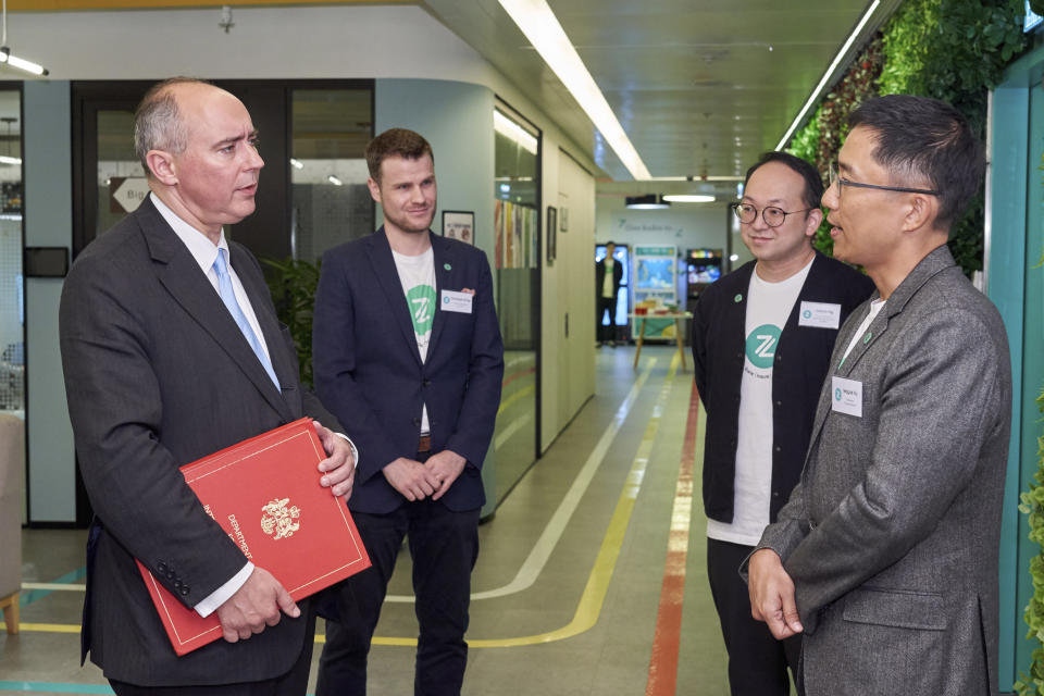 In this photo released by the Hong Kong Cyberport, Dominic Johnson, British minister of state in the Department for Business and Trade, left, visits the Cyberport business park in Hong Kong, Monday, May 8, 2023. The first British minister visiting Hong Kong in five years said his country will not "duck" its historic responsibilities to people living in its former colony while engaging with China in areas they share common interests. (Hong Kong Cyberport via AP)