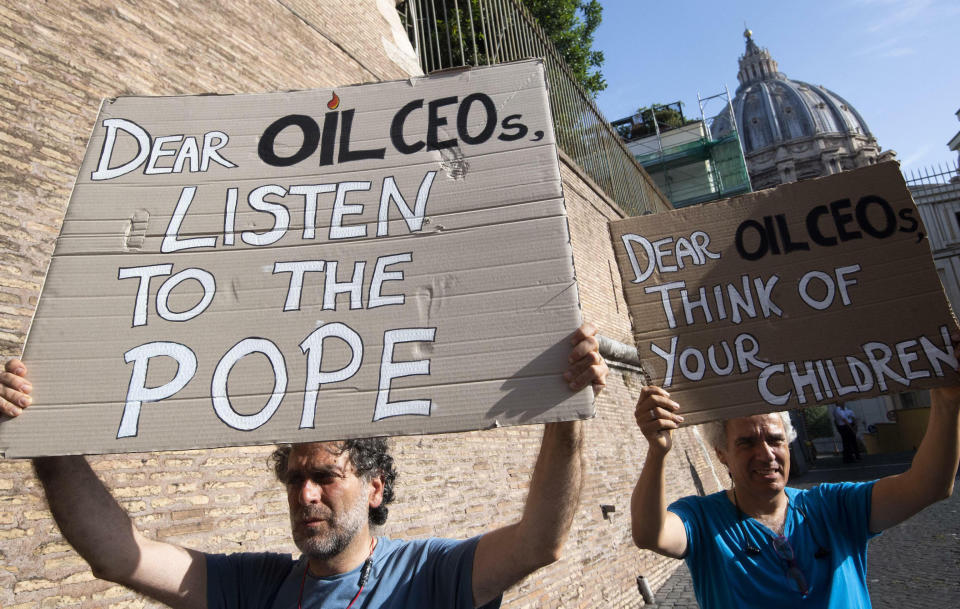 Activists hold up signs outside the Vatican as Pope Francis meets with oil executives, Friday, June 14, 2019. The meeting marked the second year that Francis has invited oil and financial sector executives to the Vatican to impress upon them his concern that preserving God’s creation is one of the fundamental challenges facing humankind today. (Claudio Peri/ANSA via AP)