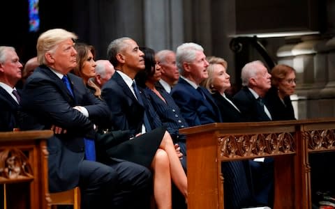 Donald Trump, Barack Obama, Bill Clinton and Jimmy Carter and their wives sit together for George H W Bush's funeral - Credit: ALEX BRANDON/AFP