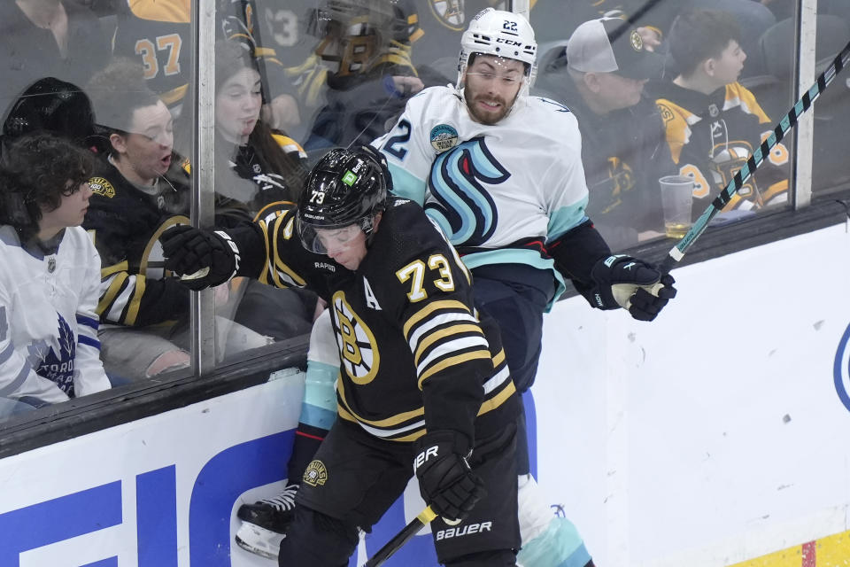 Boston Bruins defenseman Charlie McAvoy (73) and Seattle Kraken right wing Oliver Bjorkstrand (22) slam into the boards in the first period of an NHL hockey game, Thursday, Feb. 15, 2024, in Boston. (AP Photo/Steven Senne)