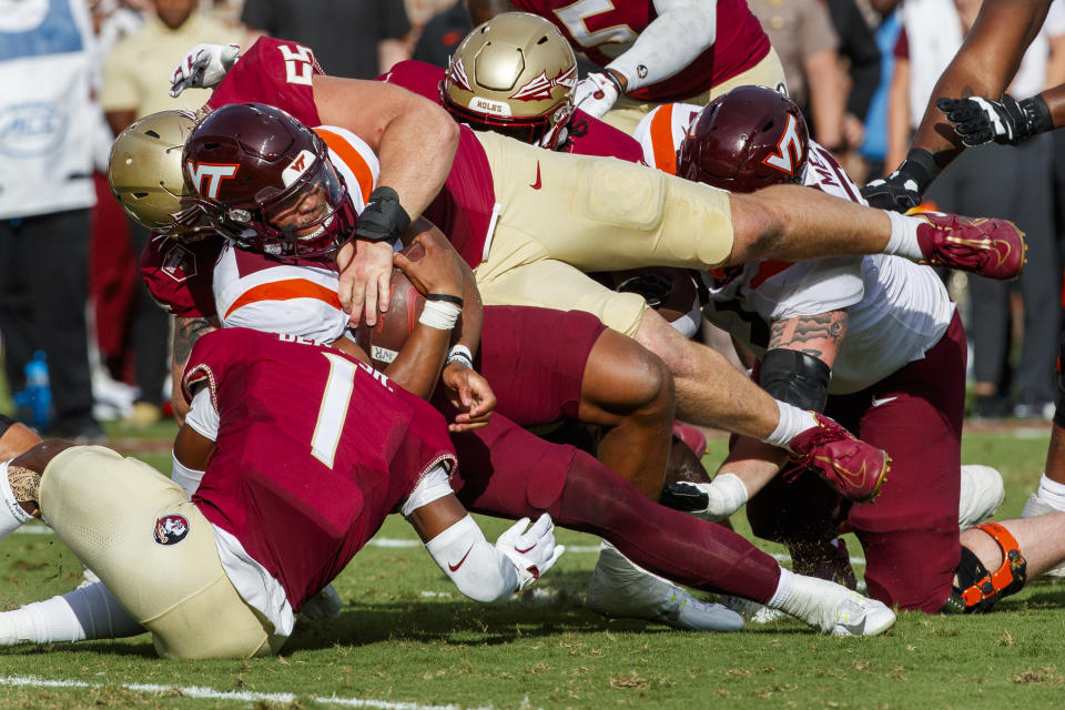 Virginia Tech quarterback Kyron Drones (1) is sandwiched by Florida State's defensive back Akeem Dent (1) and defensive lineman Braden Fiske (55) during the first half of an NCAA college football game, Saturday, Oct. 7, 2023, in Tallahassee, Fla. (AP Photo/Colin Hackley)