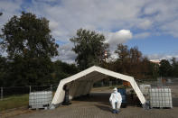 A health care worker in full protective gear, waits to conduct a COVID-19 test at a drive-in sampling station in Prague, Czech Republic, Wednesday, Oct. 7, 2020. Coronavirus infections in the Czech Republic hit a new record high, surpassing 4,000 cases in one day for the first time. (AP Photo/Petr David Josek)