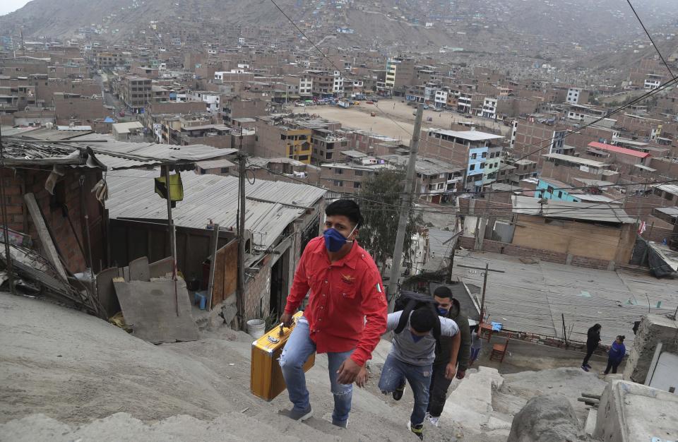 Josue Yacahuanca, a 21-year-old barber, his briefcase of tools in hand, ascends a flight of stairs in the San Juan de Lurigancho neighborhood of Lima, Peru, Friday, June 19, 2020. In the midst of one of the worst recessions in the western hemisphere due to an extensive quarantine to curb the spread of the new coronavirus, the barber offers free haircuts in Lima's working class neighborhoods. (AP Photo/Martin Mejia)