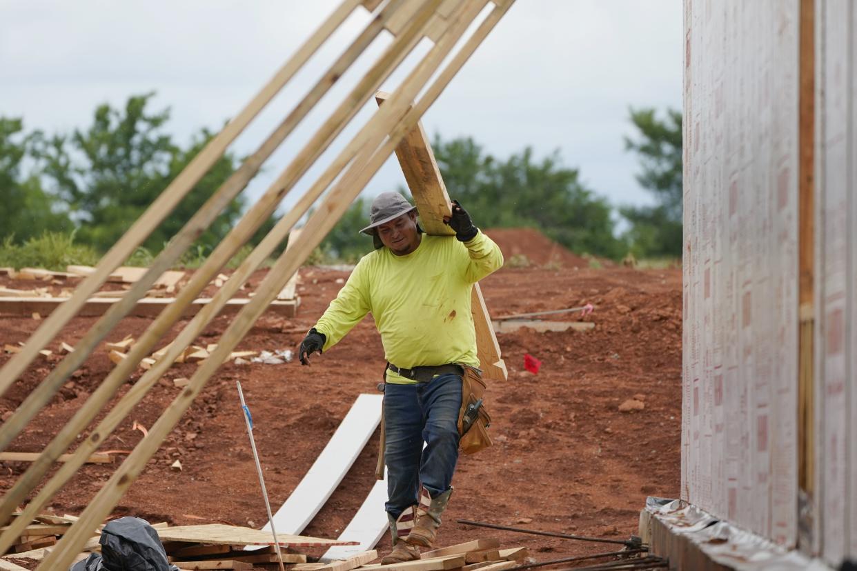 A worker carries a board at a home construction site June 29, 2021, in Piedmont, Okla. 