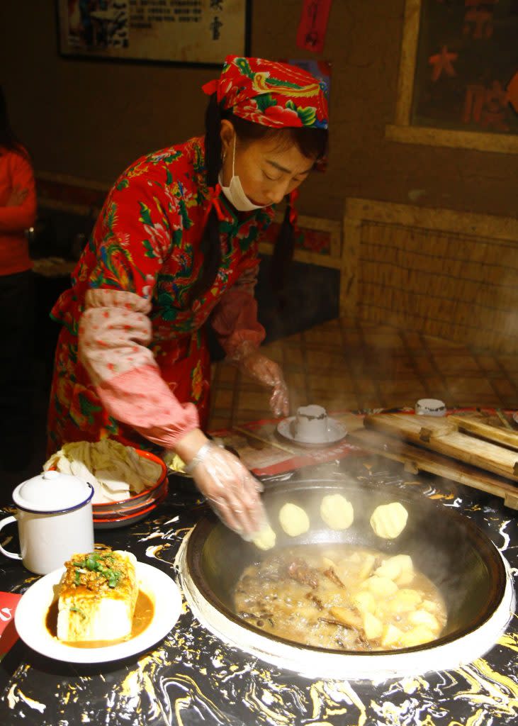 美女服務員在鐵鍋邊貼一圈玉米餅，過程充滿儀式感。