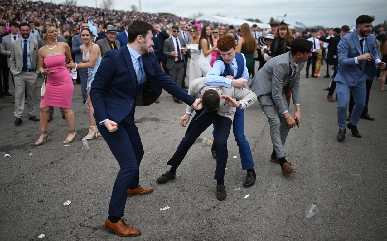 Female racegoers look on bemused as fighting breaks out