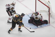 Chicago Blackhawks goalie Corey Crawford (50) makes the save on Vegas Golden Knights' William Carrier (28) as Blackhawks' Calvin de Haan (44) defends during the second period in Game 1 of an NHL hockey Stanley Cup first-round playoff series, Tuesday, Aug. 11, 2020, in Edmonton, Alberta. (Jason Franson/The Canadian Press via AP)