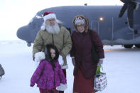 Santa and Mrs. Claus pose with a child who braved winds chills of about minus 25 degrees to greet them when they landed Tuesday, Nov. 29, 2022, in Nuiqust, Alaska. Operation Santa Claus, the Alaska National Guard's outreach program, attempts to bring Santa and Mrs. Claus and gifts to children in two or three Alaska Native villages each year, including Nuiqsut in 2022. (AP Photo/Mark Thiessen)