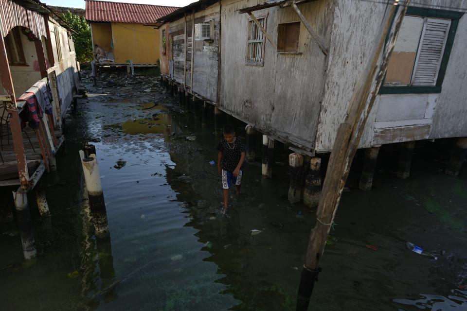 A boy walks between stilt houses, on the water's edge of Lake Maracaibo in the Santa Rosa de Agua neighborhood of Maracaibo, Venezuela, Tuesday, Aug. 8, 2023. The pollution around the lake, one of Latin America's largest, is the result of decades of excessive oil exploitation on its bed, inadequate maintenance, and a lack of investment to improve an already obsolete infrastructure, according to environmentalists. (AP Photo/Ariana Cubillos)