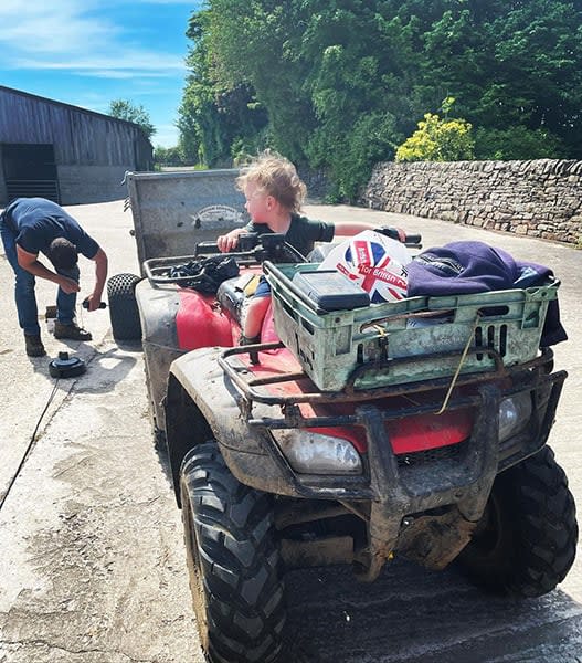 Liz and Kelvins son sits on a tractor at their farm