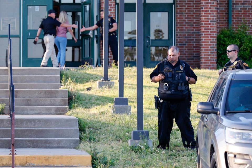 Law enforcement stand outside of Henryetta High School on Monday, May 1, 2023, as people arrive for a vigil after Okmulgee County Sheriff reported seven people dead after a search for two missing teenage girls.