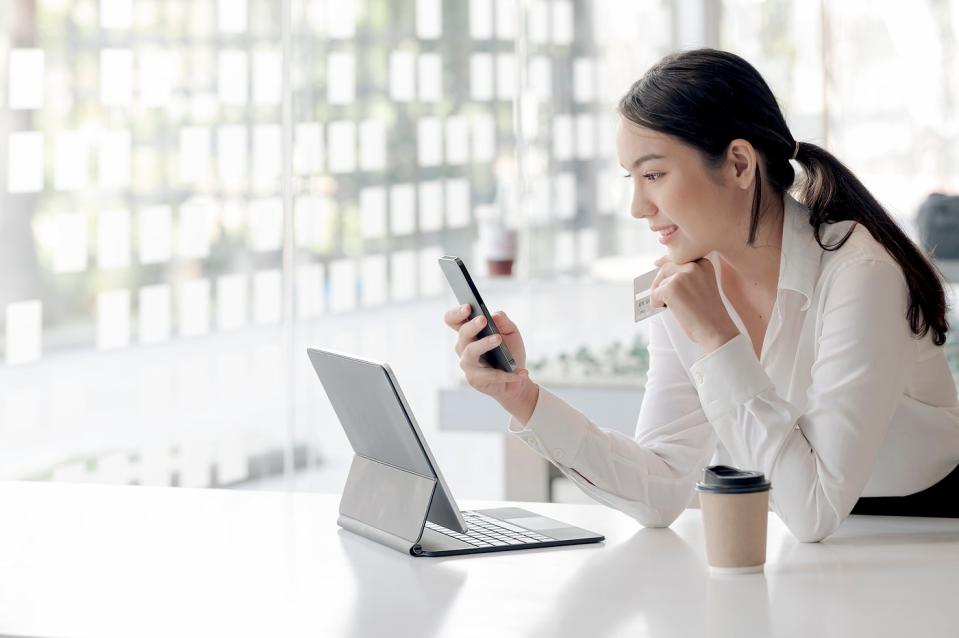 A person checks a phone and a laptop computer in a coffee shop.