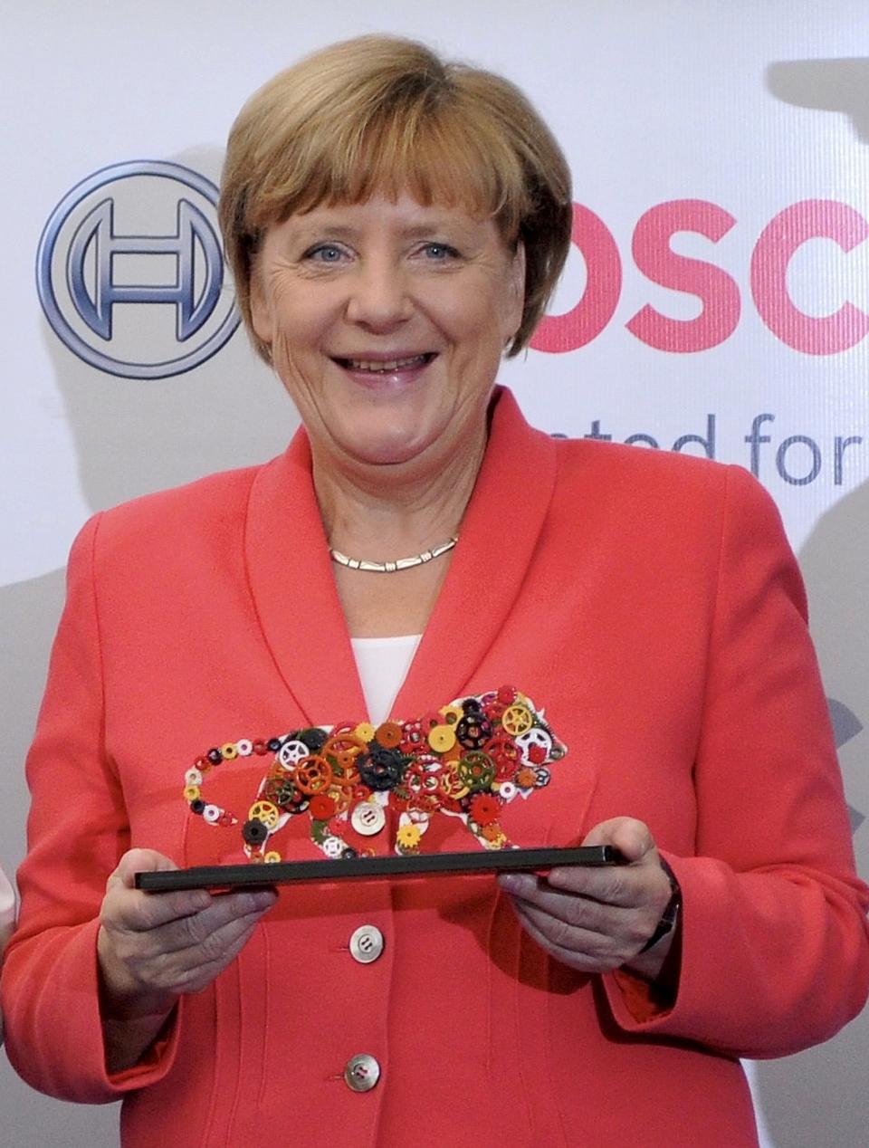 German Chancellor Merkel smiles as she holds a souvenir during a photo opportunity after her visit to the Bosch Vocational Center in Bengaluru