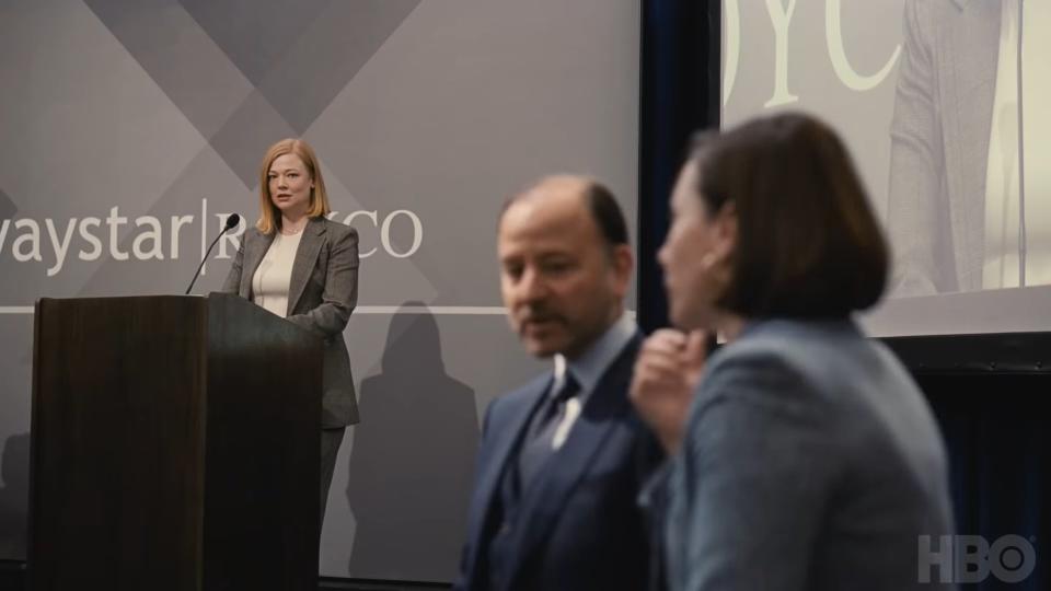 Shiv at the podium looking worried with Hugo, and Karolina on the side trying to figure it out