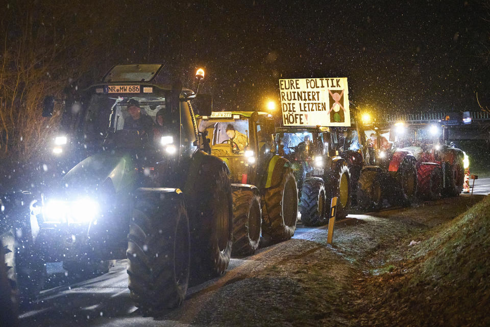 Farmers with tractors protest against the federal government's austerity measures and block an access road to the A3 highway in Neustadt/Wied, Rhineland-Palatinate, Germany, Monday, Jan. 8, 2024. A sign on one of the tractors reads "Your policies are ruining the last farms!". Farmers blocked highway access roads in parts of Germany Monday and gathered for demonstrations, launching a week of protests against a government plan to scrap tax breaks on diesel used in agriculture. (Thomas Frey/dpa/dpa via AP)