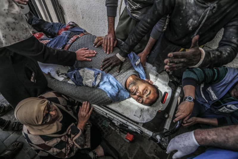 Palestinians surround the body of a UN  staff who was killed in an Israeli air strike near a warehouse of the United Nations Relief and Works Agency for Palestine Refugees (UNRWA), at Al-Najjar Hospital in Rafah, southern Gaza Strip. Abed Rahim Khatib/dpa