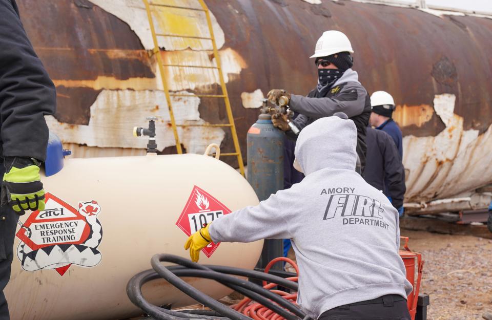 Firefighters from the United States and Canada work with pressurized hoses and tanks as part of a training into how to offload or "flare" a leaking railroad tanker car at the Security and Emergency Response Training Center in Pueblo, Colorado.