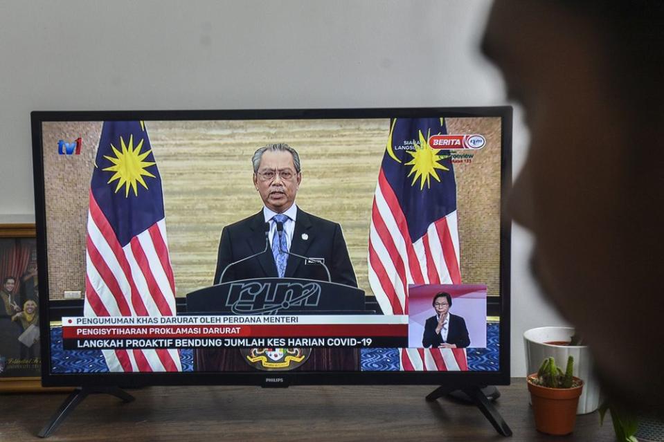 A man watches a live telecast of Prime Minister Tan Sri Muhyiddin Yassin's speech in Kuala Lumpur January 12, 2020. Muhyiddin said the government does not expect as severe an economic impact as seen with the first MCO implemented in the second quarter of 2020, as more economic activities are allowed to operate. — Picture by Miera Zulyana