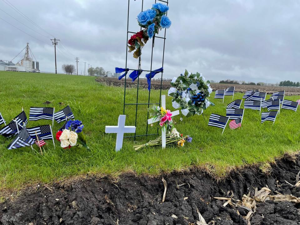 Flags, flowers and crosses mark the site where Knox County Sheriff's Deputy was struck and killed by a car Friday, April 29, 2022