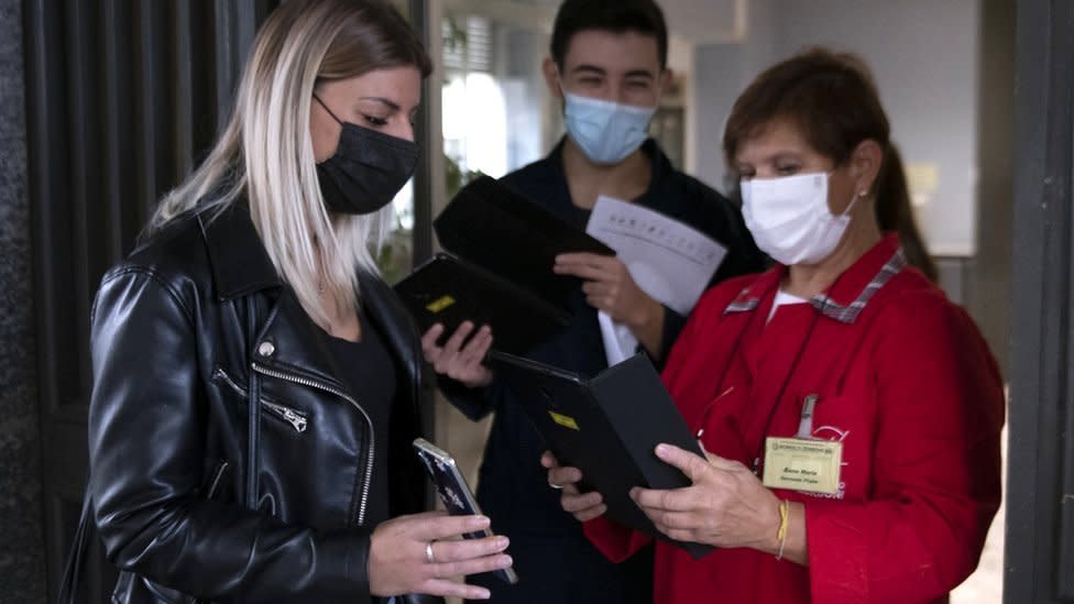 Personal de un colegio muestra el "pase verde" en Turín.