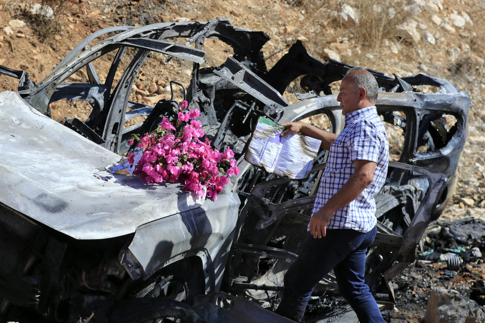 Samir Ayoub, uncle of three children who were killed by an Israeli airstrike, puts flowers and a burning book on their car in the town of Ainata, a Lebanese border village with Israel in south Lebanon, Monday, Nov. 6, 2023. An Israeli airstrike in south Lebanon on Sunday, Nov. 5, 2023 evening killed four civilians, including a woman and three children, raising the likelihood of a dangerous new escalation in the conflict on the Lebanon-Israel border. (AP Photo/Mohammed Zaatari)
