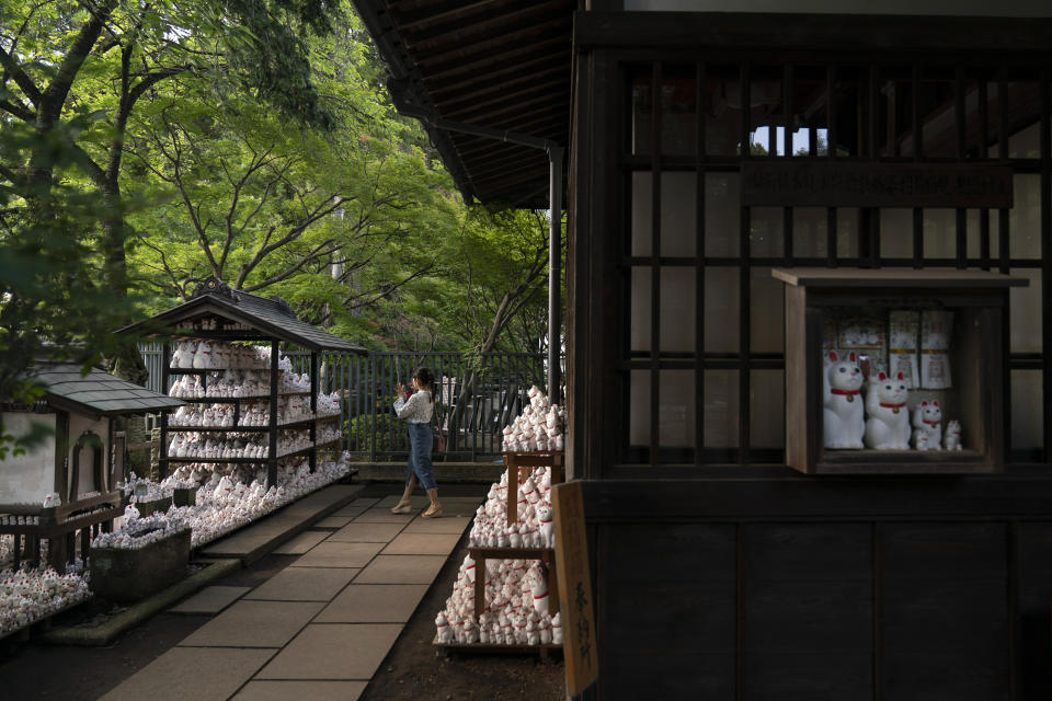 In this June 25, 2019, photo, a visitor takes photos of beckoning cat figurines at Gotokuji Temple in Tokyo. According to a centuries-old legend provided by the temple, Gotokuji, a Buddhist temple located in the quiet neighborhood of Setagaya, is the birthplace of beckoning cats, the famous cat figurines that are widely believed to bring good luck and prosperity to home and businesses. Some visitors come just to snap a few photos, while others make a trip to the temple to pray and make wishes. (AP Photo/Jae C. Hong)