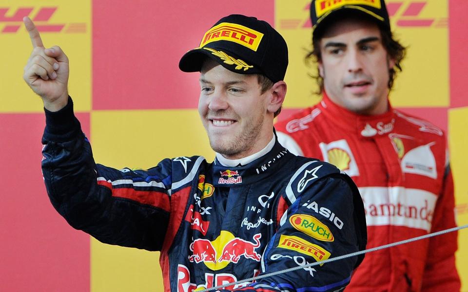 Red Bull-Renault driver Sebastian Vettel of Germany (L) raises his finger to make the "number one" sign in front of second-placed Ferrari driver Fernando Alonso of Spain (R) on the podium after coming third in the Formula One Japanese Grand Prix in Suzuka on October 9, 2011. - AFP/TORU YAMANAKA 